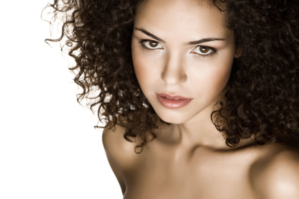 Image of a curly brazilian model wearing soft red lipstick and red blush.